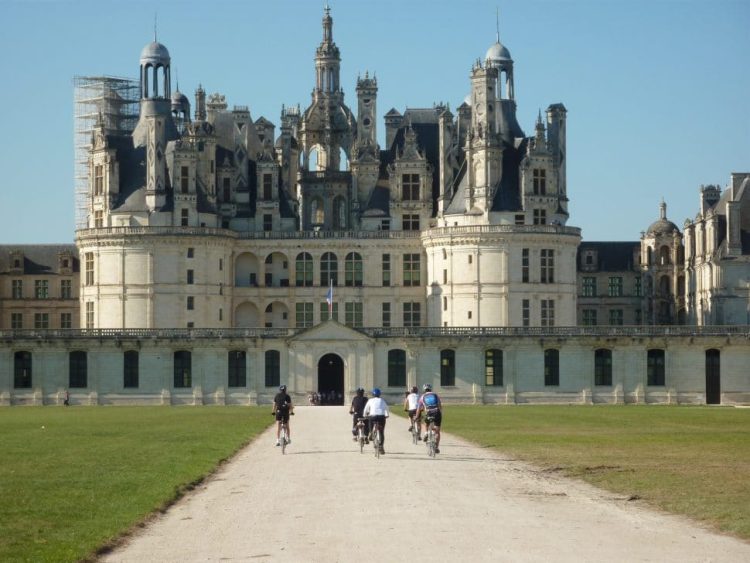 cyclists ride towards the castle of chambord