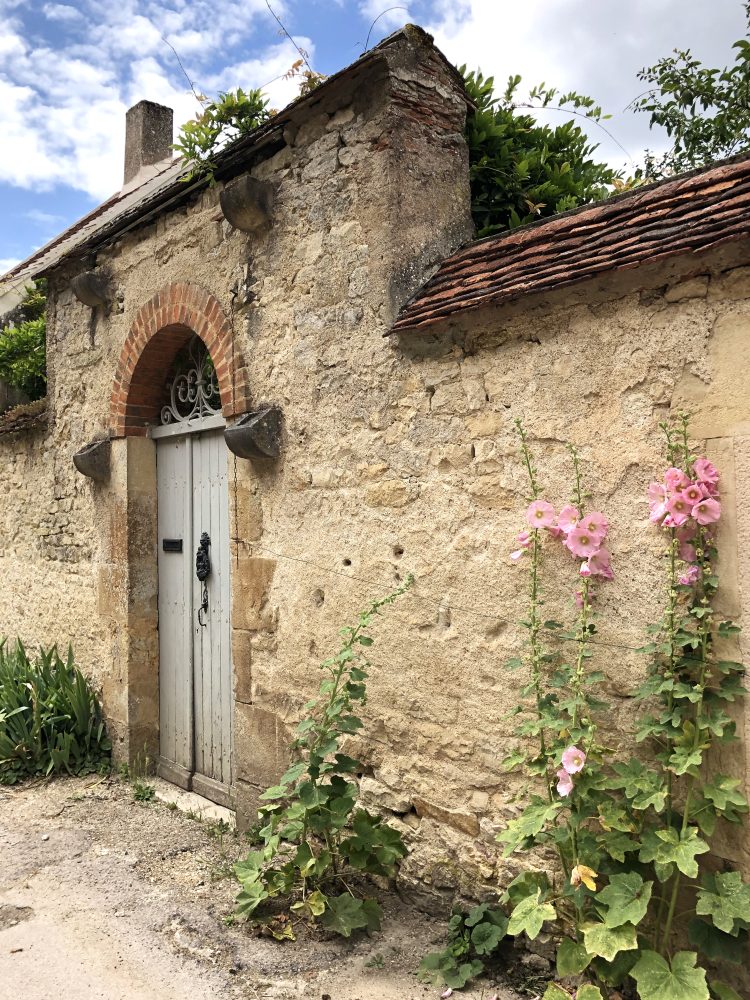 une porte grise avec des fleurs sur la mur à vézelay